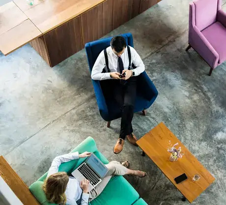 Two individuals seated in office chairs, engaged in conversation within a professional workspace.