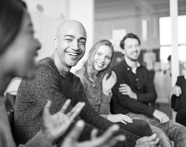 A diverse group of individuals engaged in discussion around a conference table in a meeting room.