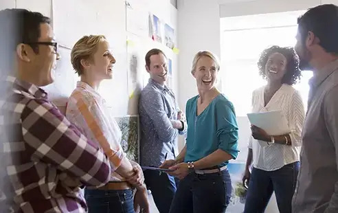 A diverse group of individuals gathered around a whiteboard, engaged in discussion and collaboration.