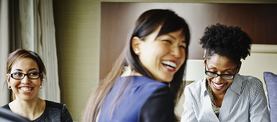 Three women joyfully smiling and laughing together, showcasing a moment of friendship and happiness.